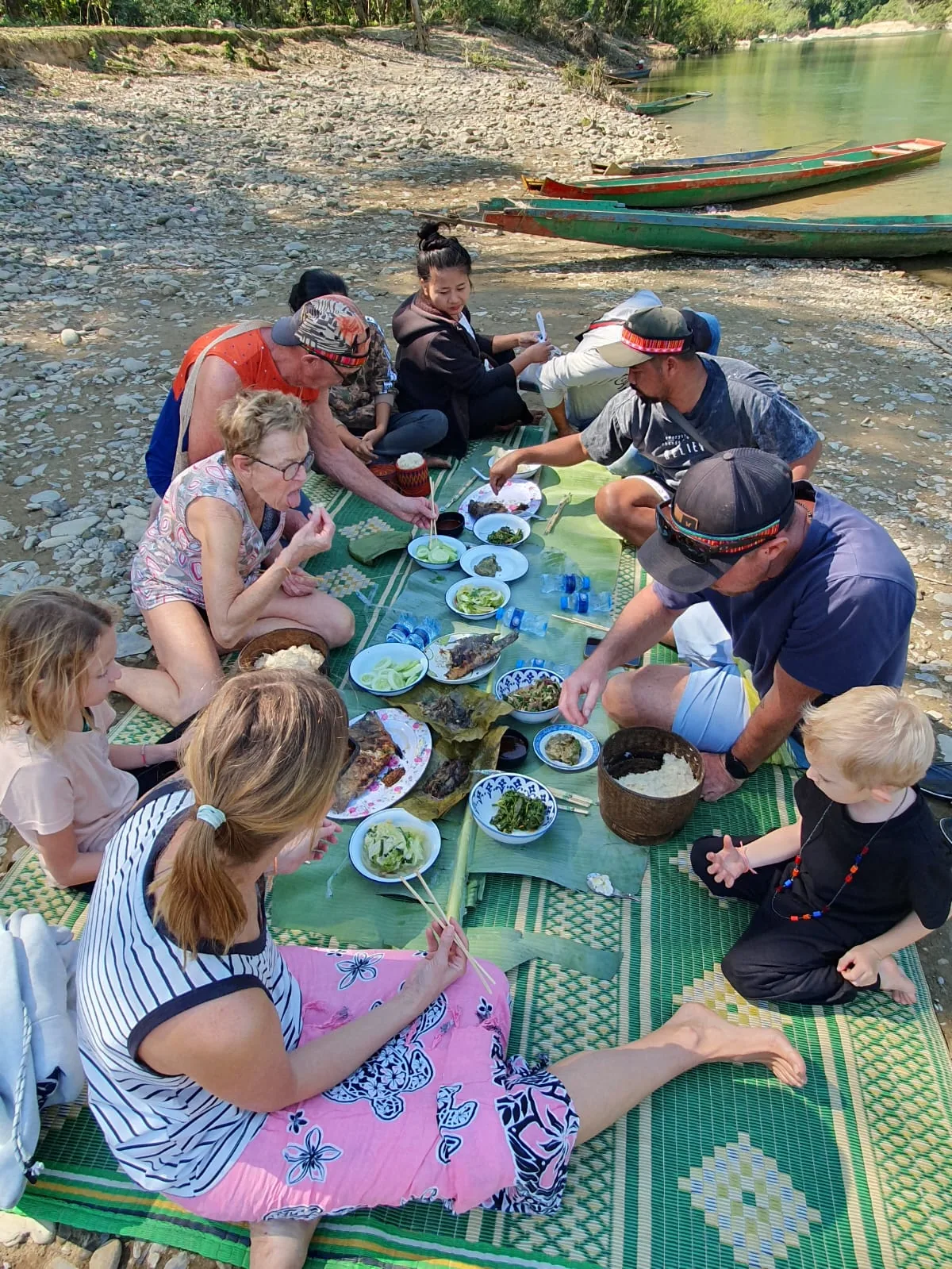 Travelers sharing a traditional Lao riverside meal